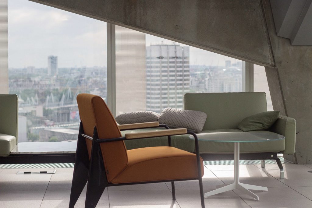 orange and green sofas in condo with glass table