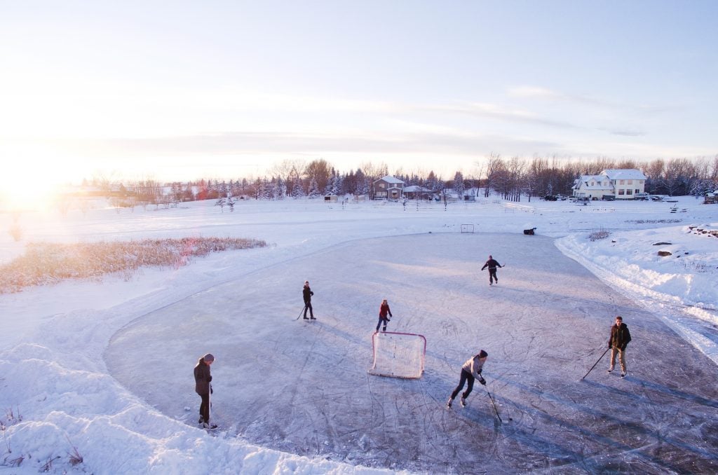 People playing hockey on frozen over pond