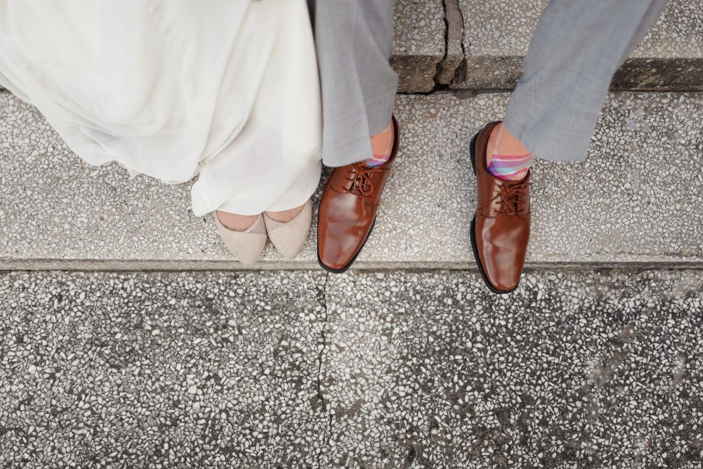 view looking down on man and woman's feet, with brown leather and beige shoes on steps