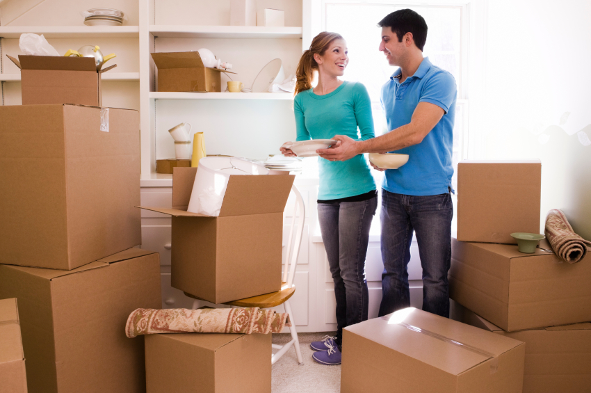 young couple surrounded by moving boxes while holding ceramic bowls